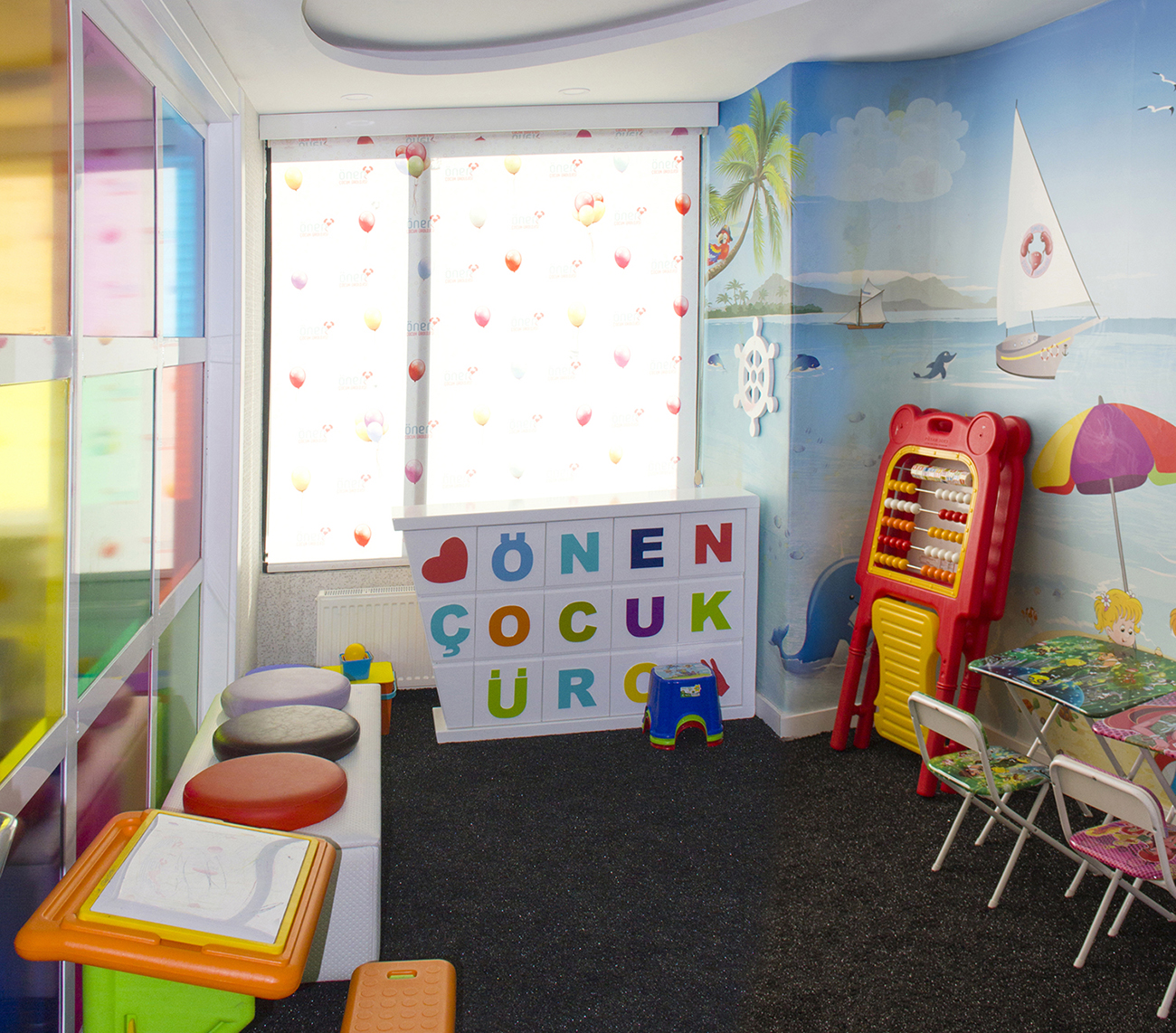 Kliniğin boş çocuk oyun köşesi; oyuncaklar, küçük sandalyeler ve renkli duvarlar